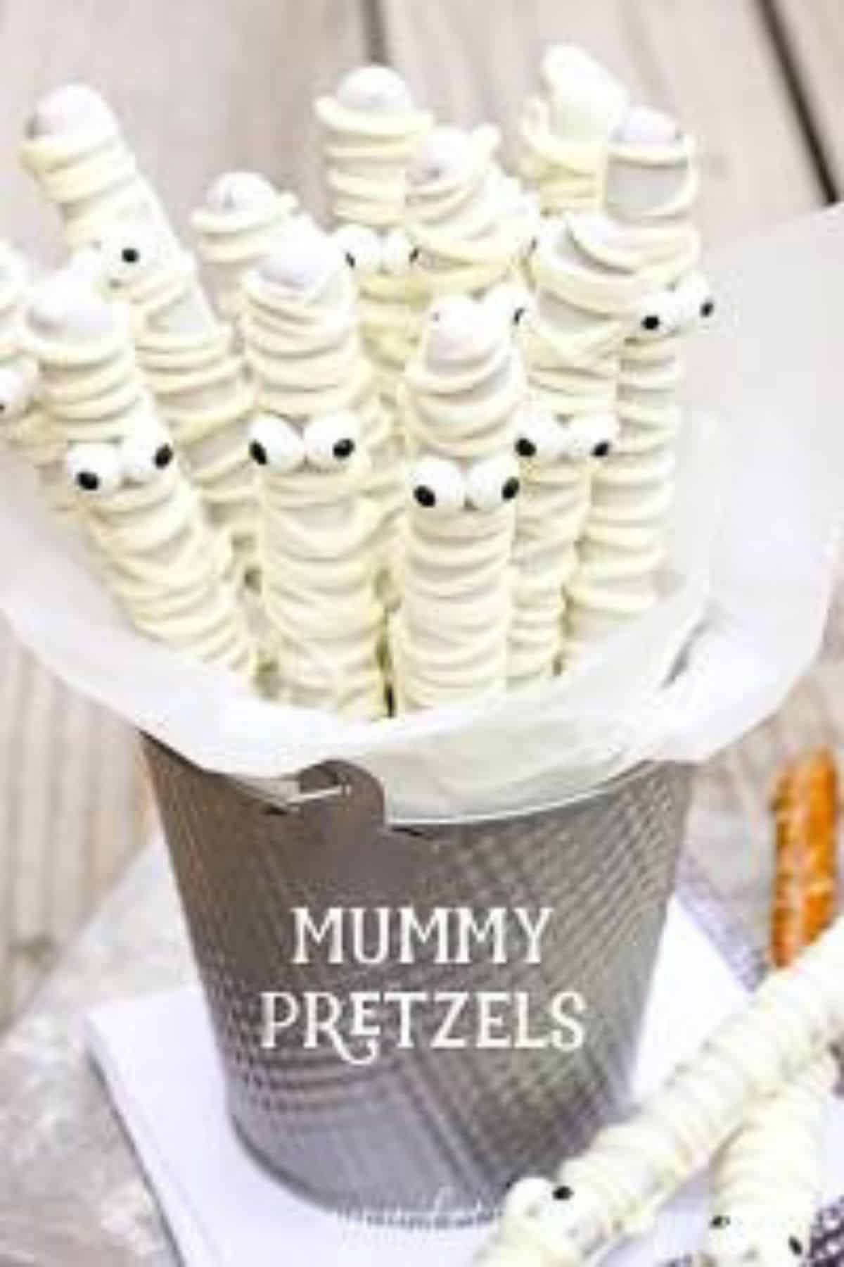 Preztels dipped in white chocolate and made to look like mummies for a halloween themed fall treat