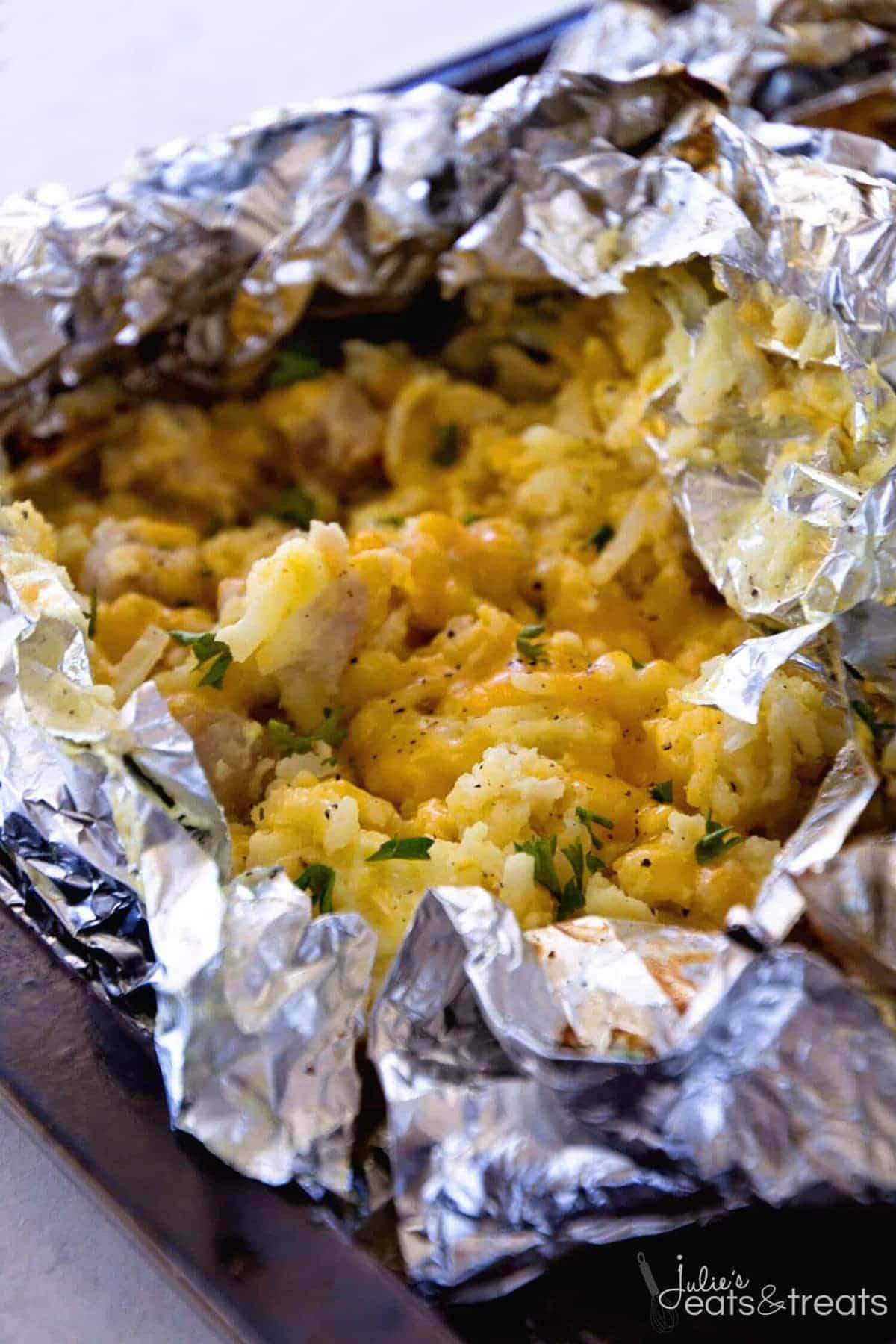 A variety of campfire meals including foil packet dinners, campfire breakfasts, and campfire desserts cooking over a fire.